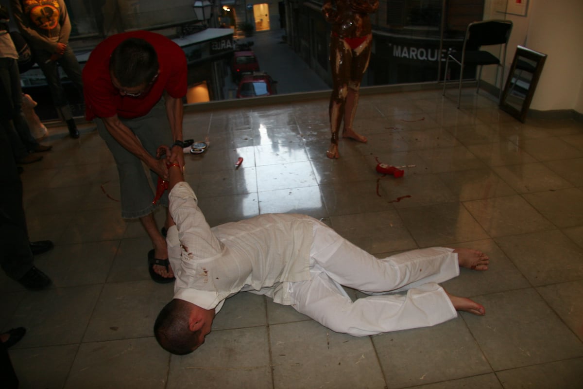 Peniche, vestido de blanco, tendido en el suelo de la sala durante la performance
